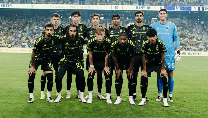 A soccer team in black and yellow uniforms posing for a group photo on a soccer field.