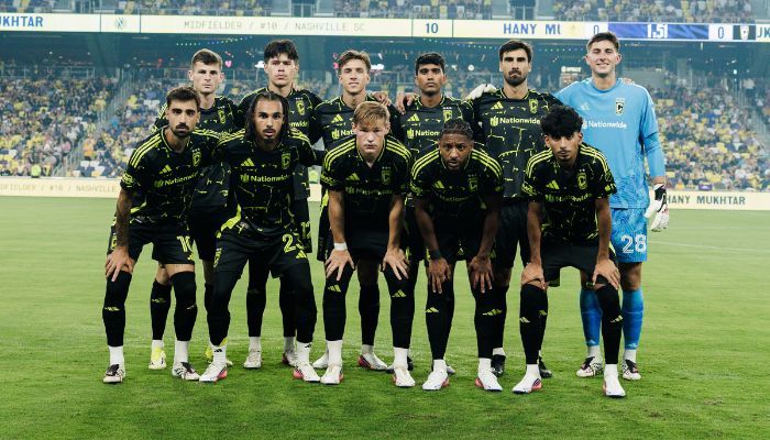 A soccer team in black and yellow uniforms posing for a group photo on a soccer field.
