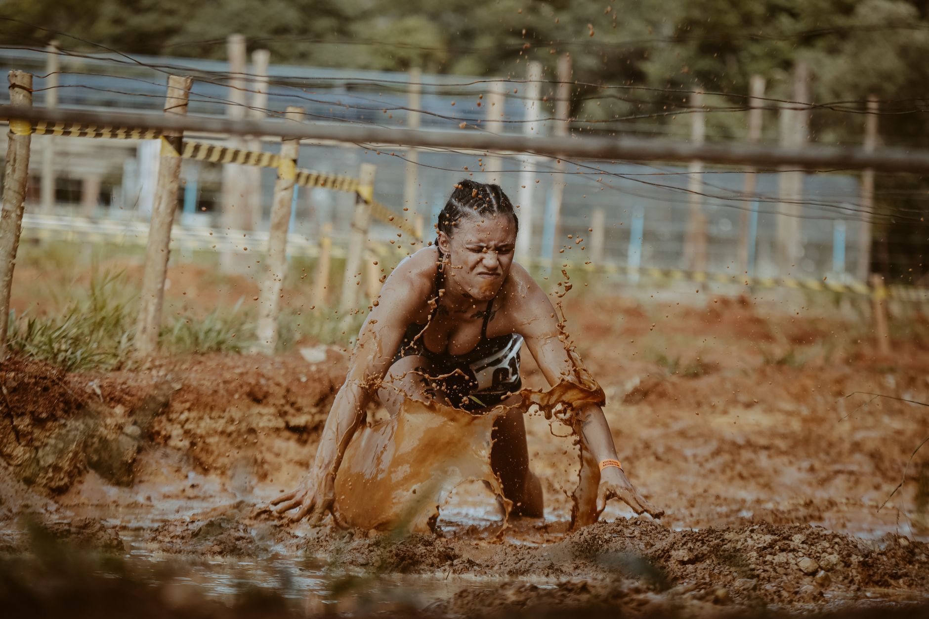 woman crawling through mud in obstacle race